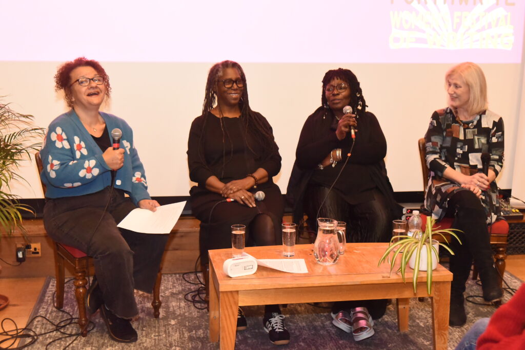 Four women on stage with Microphones